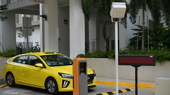 a car entering a parking zone with a speed-breaker, an anpr camera, and a digital board showing available slots for barrier-free parking. 