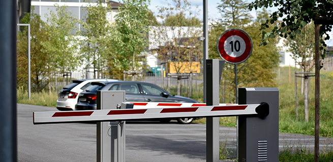 a parking zone with a boom barrier in front and cars parked in the background, showcasing cost-effective parking solutions.