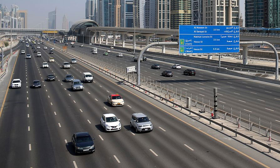 a highway with a city in the background and multiple cars passing, showcasing urban traffic and transportation solutions.