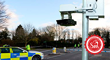Parking zone with ANPR camera on pole, monitoring vehicles, and police patrol car parked for enhanced security